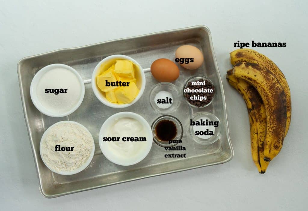 Ingredients for banana snack cake in a metal cake pan on a white counter top