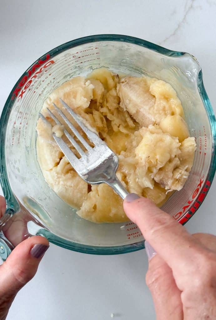 smashing bananas in a glass bowl with a fork