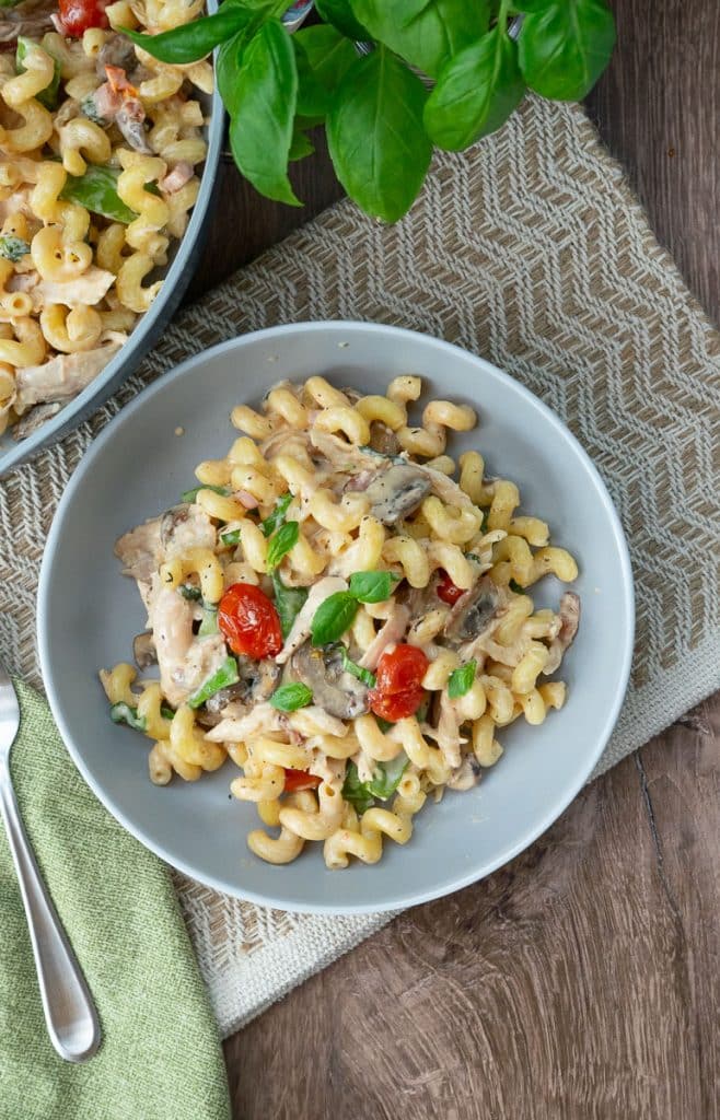 Green well mac n cheese on a plate with the pan of mac n cheese off the upper left corner of the photo
