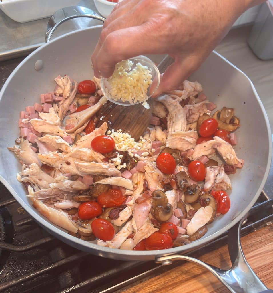 adding chicken, bacon, ham and garlic to skillet