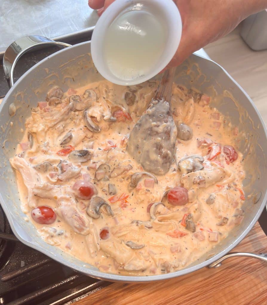 Loosening up the sauce by adding pasta water the pan