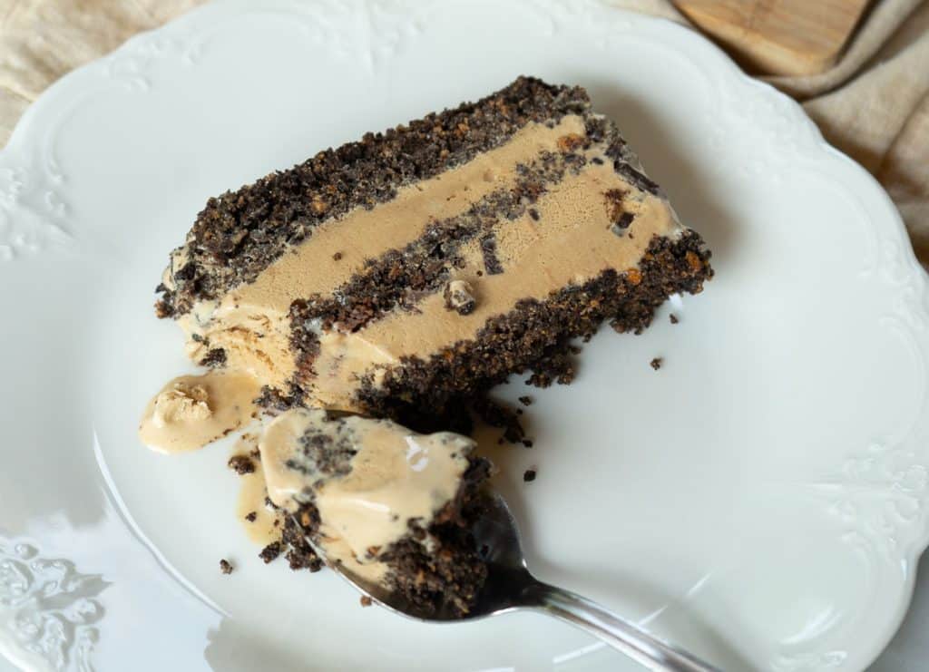 slice of coffee ice cream squares dessert on a white plate with a spoon that has a scoop