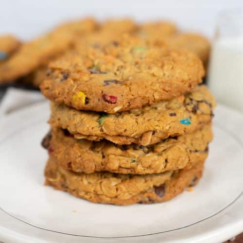stack of monster cookies on a white plate with a white background