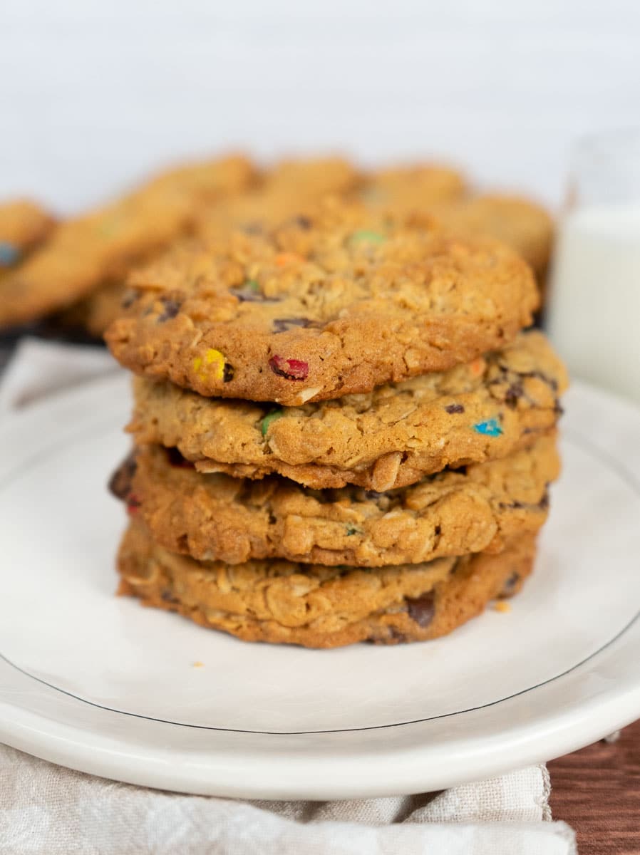 stack of monster cookies on a white plate with a white background