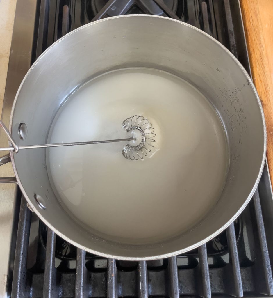 sugar and water in stainless steel pan being stirred
