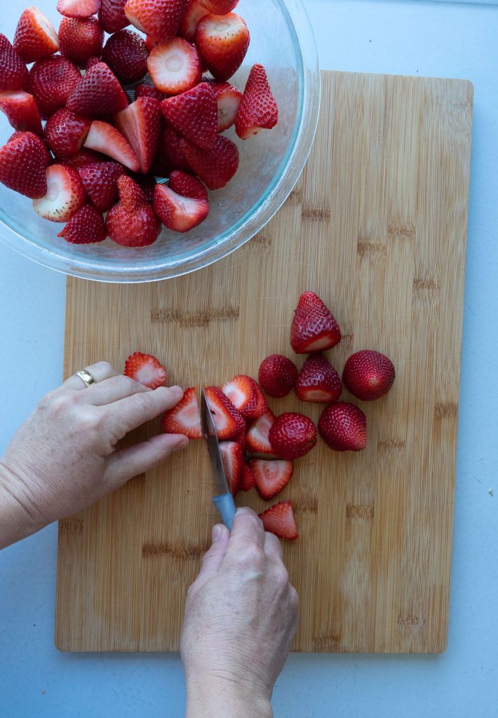 cutting strawberries on a wood cutting board