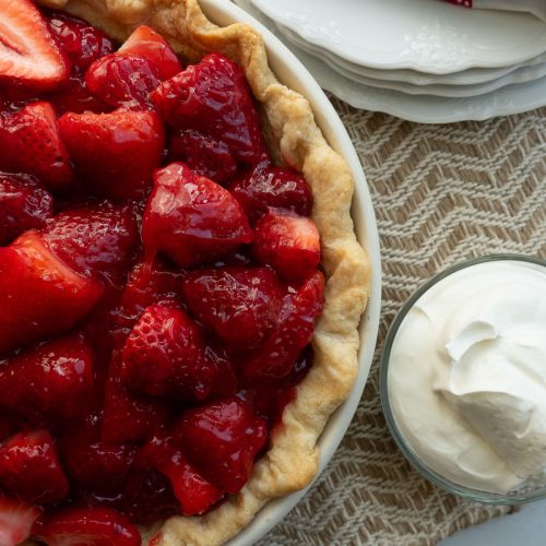 fresh strawberry pie with a bowl of whipped topping on the side