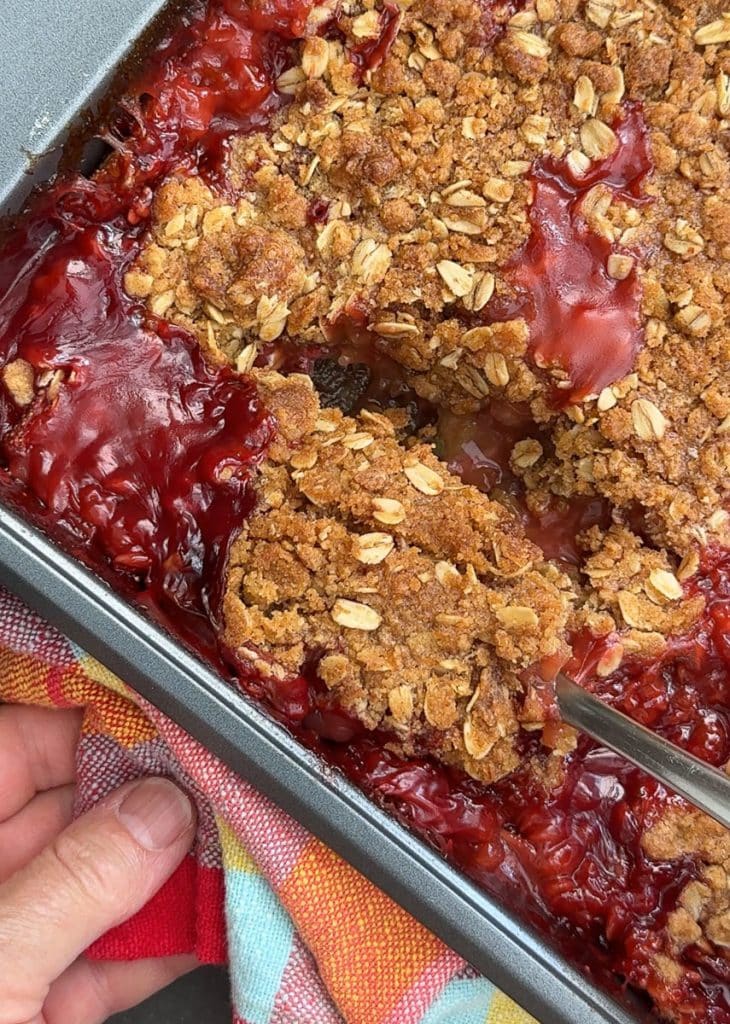 a spoon scooping out strawberry rhubarb crisp