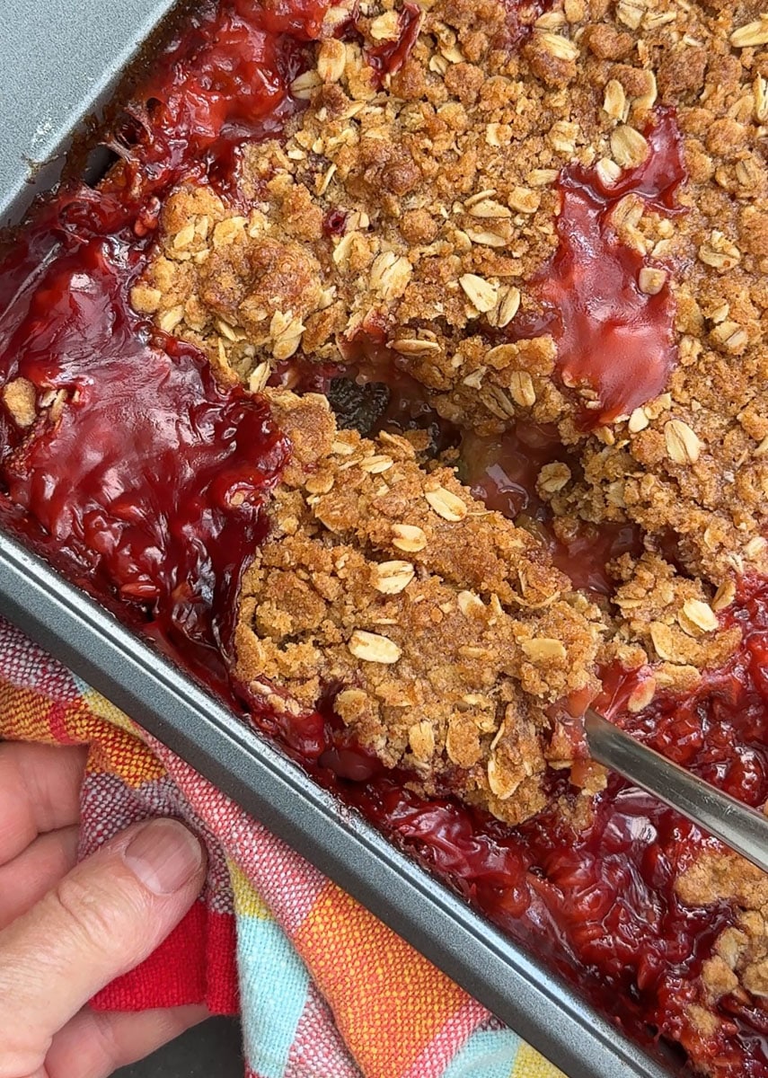 a spoon scooping out strawberry rhubarb crisp
