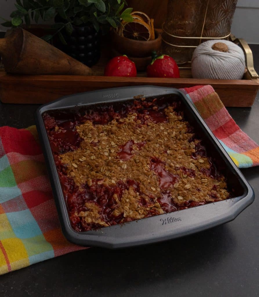 pan of strawberry rhubarb crisp on the countertop with a multi colored cloth underneath
