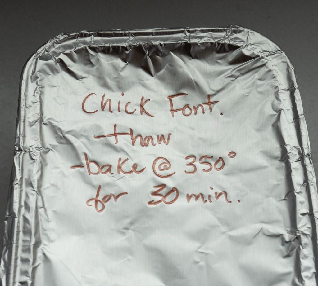 aluminum foil covered pan with freezer/baking directions written on it