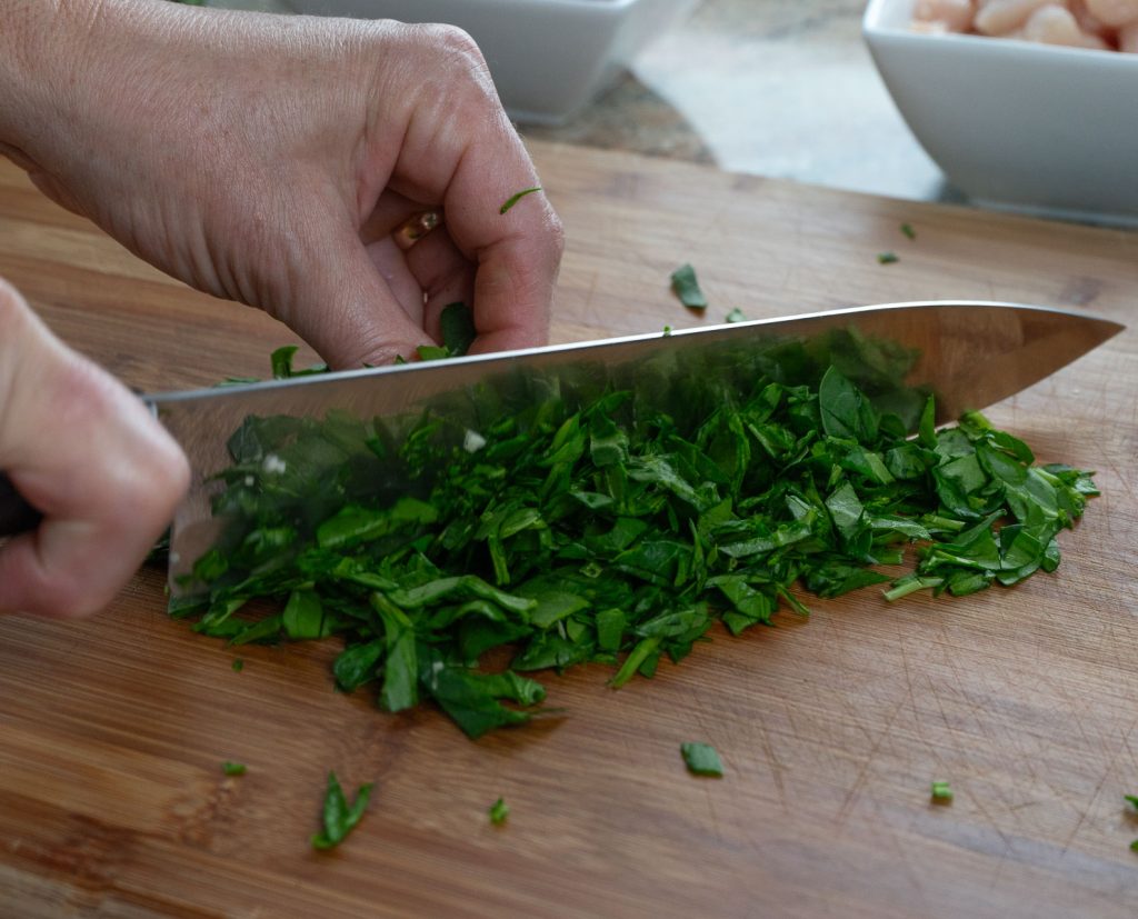 chopping spinach on a wood cutting board