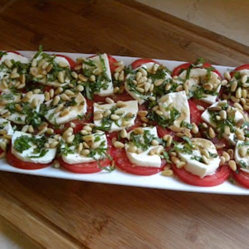 platter of mozzarella and tomatoes with basil and pinenuts
