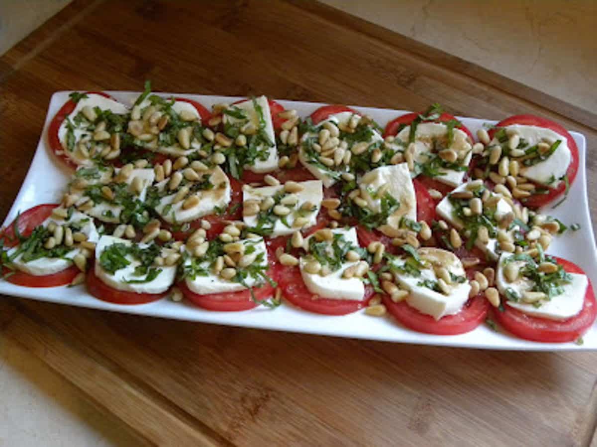platter of mozzarella and tomatoes with basil and pinenuts