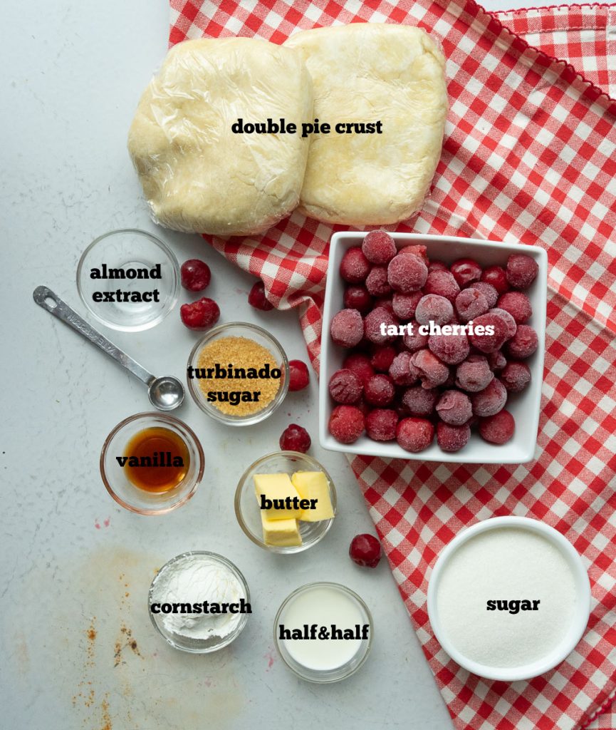 ingredients for cherry pie on a white countertop with a red checked cloth 