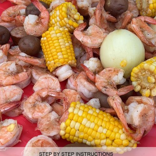 sweet corn, shrimp, red skin potatoes, and onions on a red table cloth, cooked shrimp boil out on table ready to eat