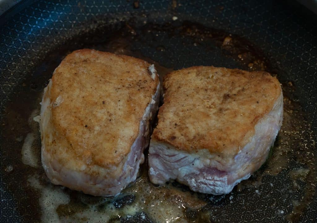 pan frying thick cut pork chops in butter in skillet on stove top