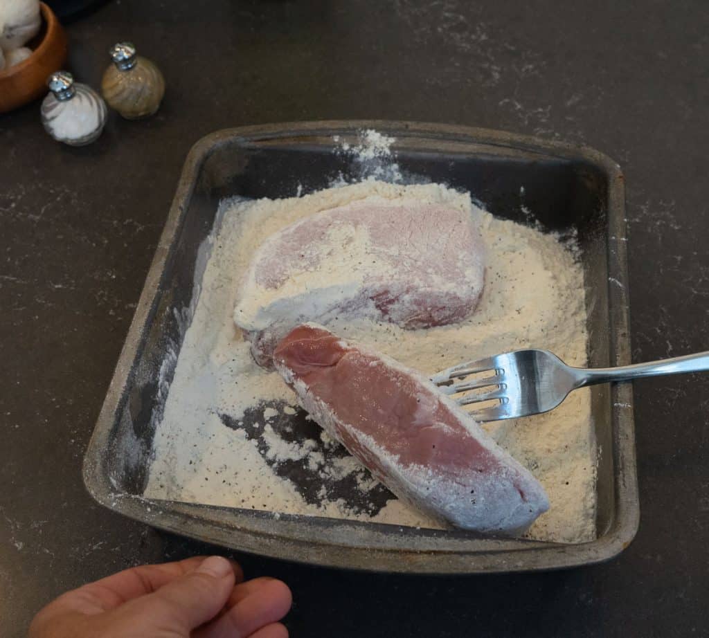 dredging pork chops in flour in a square pan