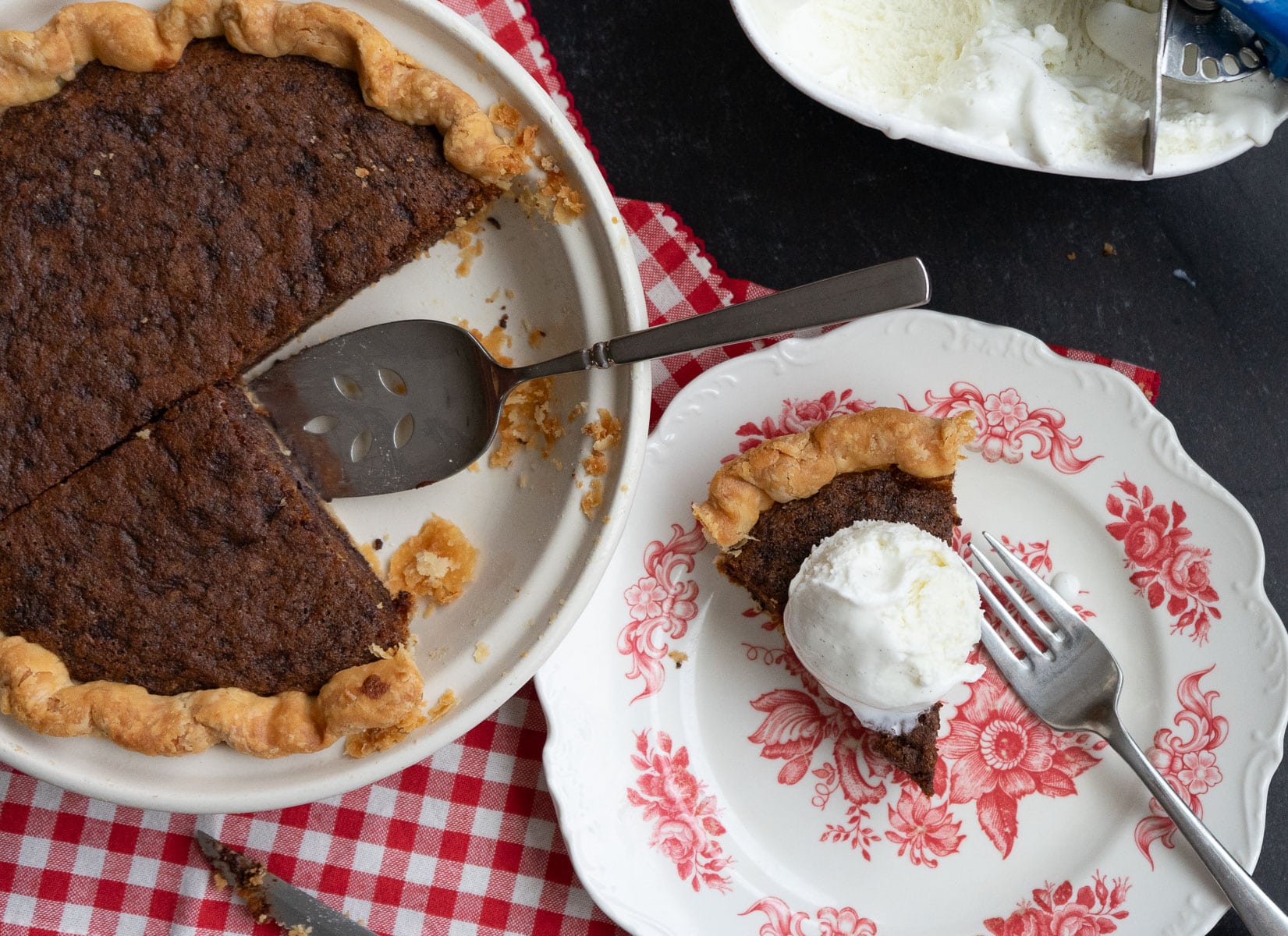toll house cookie pie with a piece removed beside a piece of toll house cookie pie on a dessert plate with ice cream on top