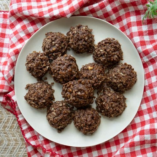top view of no bake cookies on a tan plate sitting on a red and white cloth