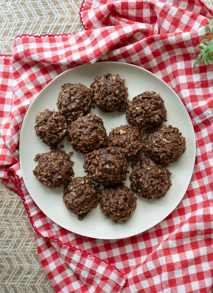 top view of no bake cookies on a tan plate sitting on a red and white cloth