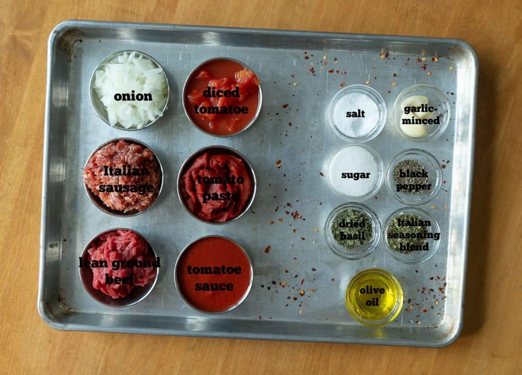 ingredients for spaghetti sauce on a baking sheet on a wood tabke