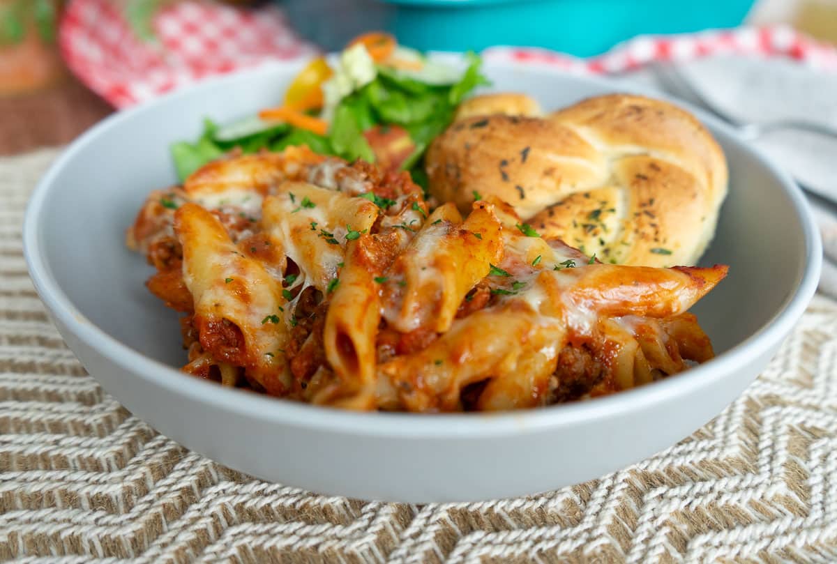 close up of a plate of mostaccioli on a tan place mat