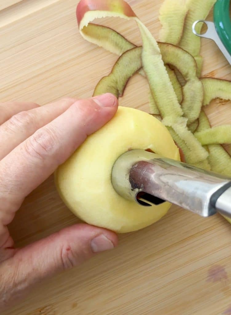 peeling and coring and apple over a wood cutting borard