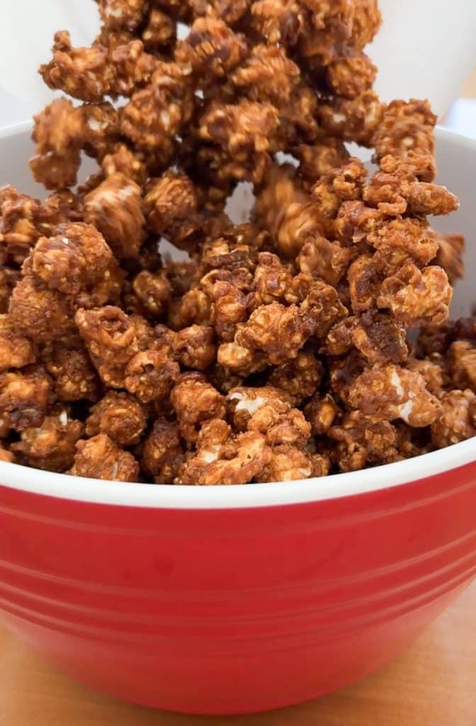 pouring cooled caramel corn into a bowl