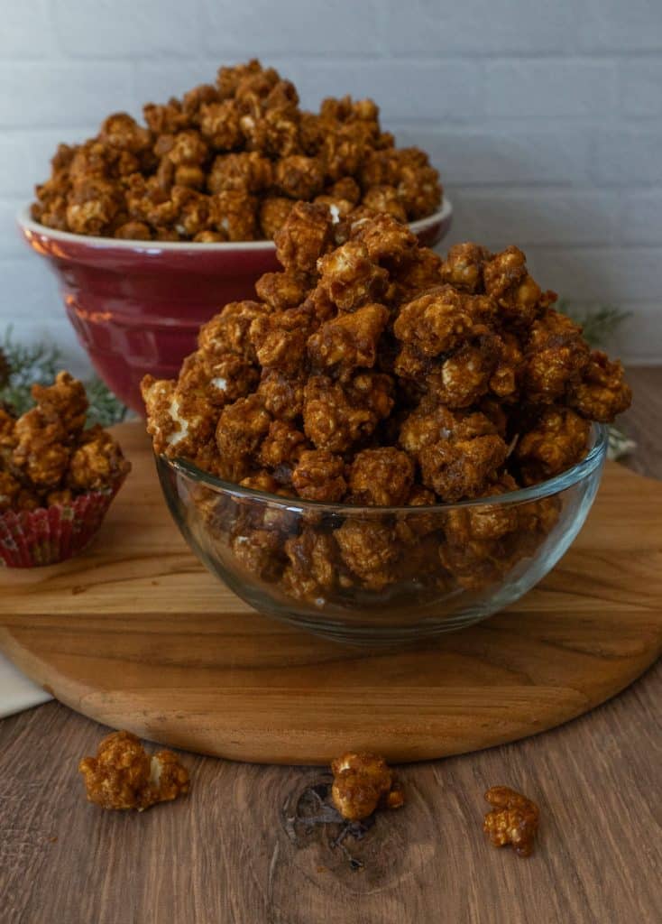 glass dish of caramel corn on a wood cutting board