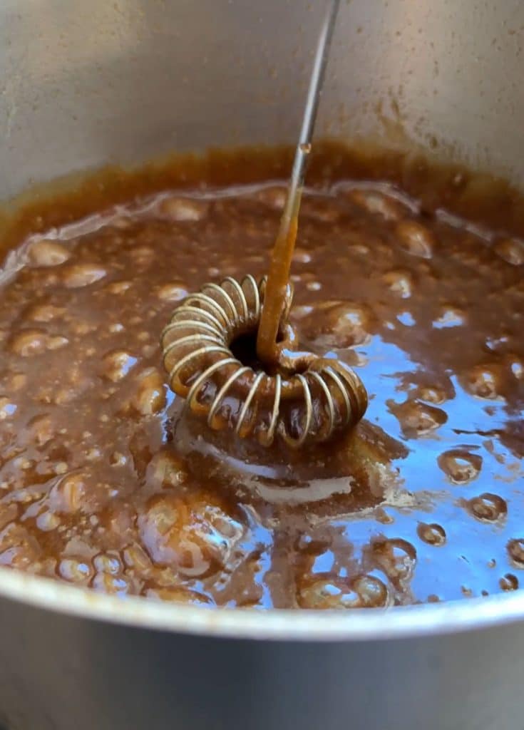 Caramel in a saucepan with a whisk hovering over the caramel