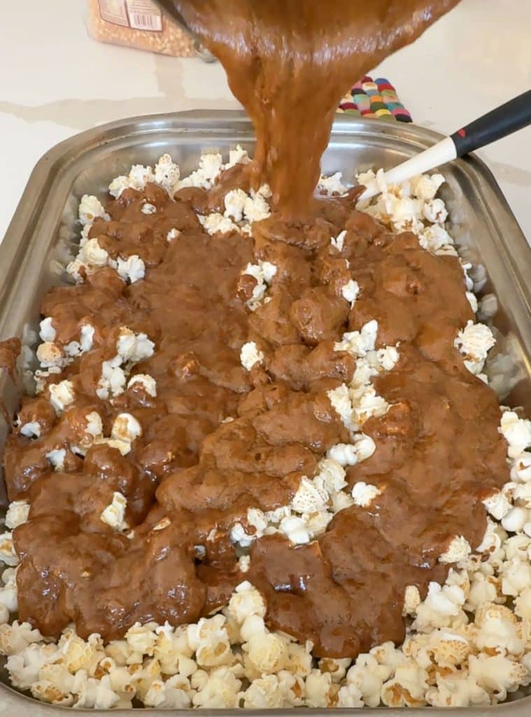pouring caramel over popcorn in a roasting pan