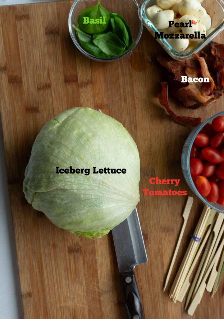 Iceberg lettuce, basil leaves, pearl mozzarella, bacon, cherry tomatoes on a wood cutt