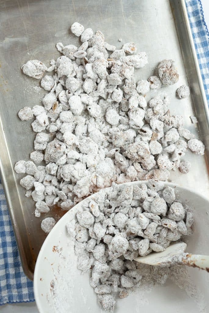 dumping puppy chow out on to baking sheet from bowl