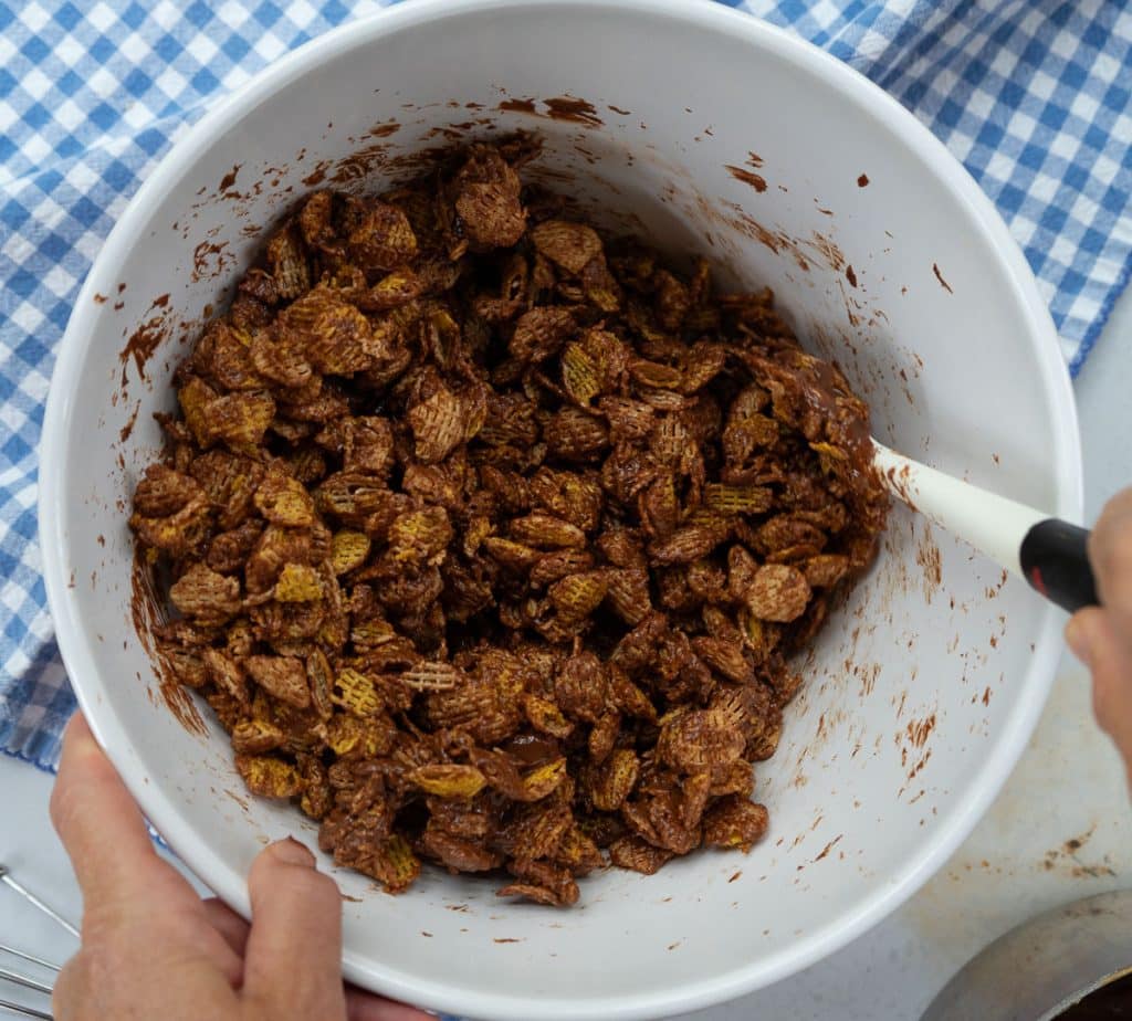 stirring melted chocolate peanut butter into crispex cereal