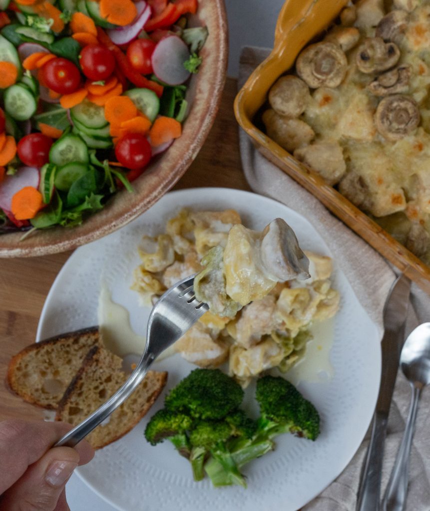 Plated chicken tortellini with broccoli green salad in uper left hand corner, and casserole dish in right upper corner