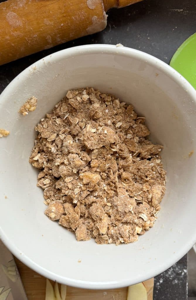 bowl with oatmeal and brown sugar crumble mixture for the crunch layer in the caramel apple crunch pie