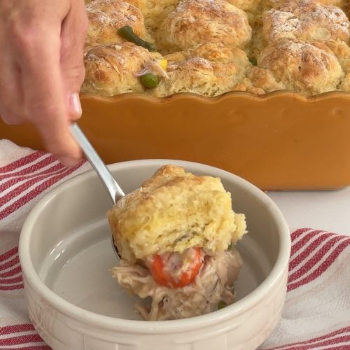 Chicken and biscuits being served from baking dish to a bowl