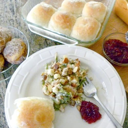 plated chicken supreme with a dinner roll and a spoonful of cranberry sauce on a plate with a fork