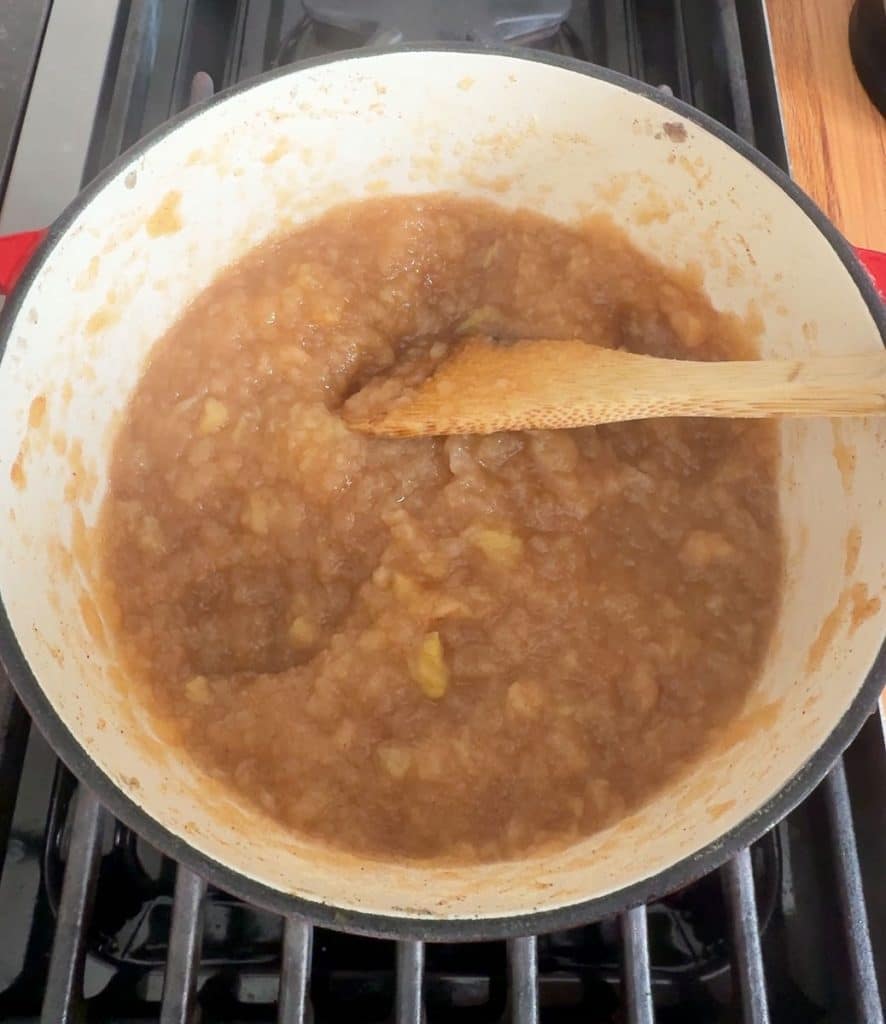 finished applesauce in a red cast iron pot on the stove