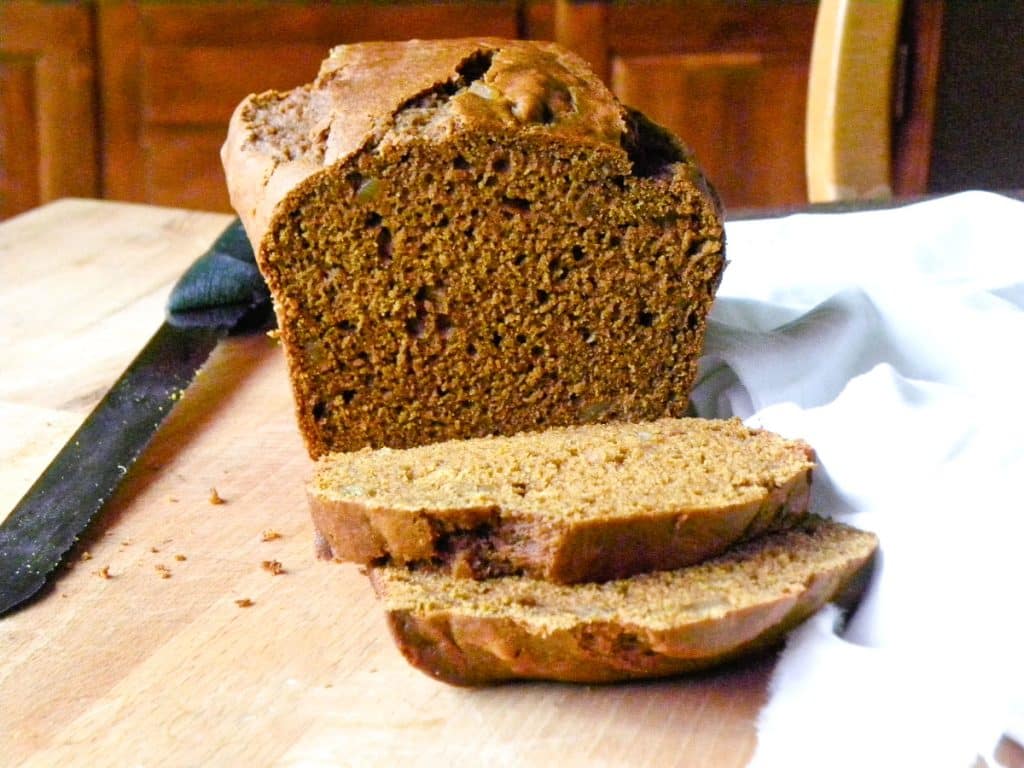 DSCN5269 pumpkin gingerbread on a wood cutting board sliced with a white tea towel in the lower right corner and a serrated knife in the top of the photo