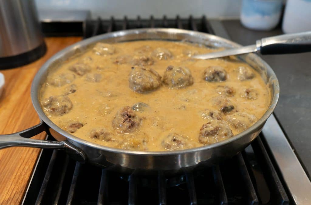 adding meatballs to swedish meatball gravy on the stovetop