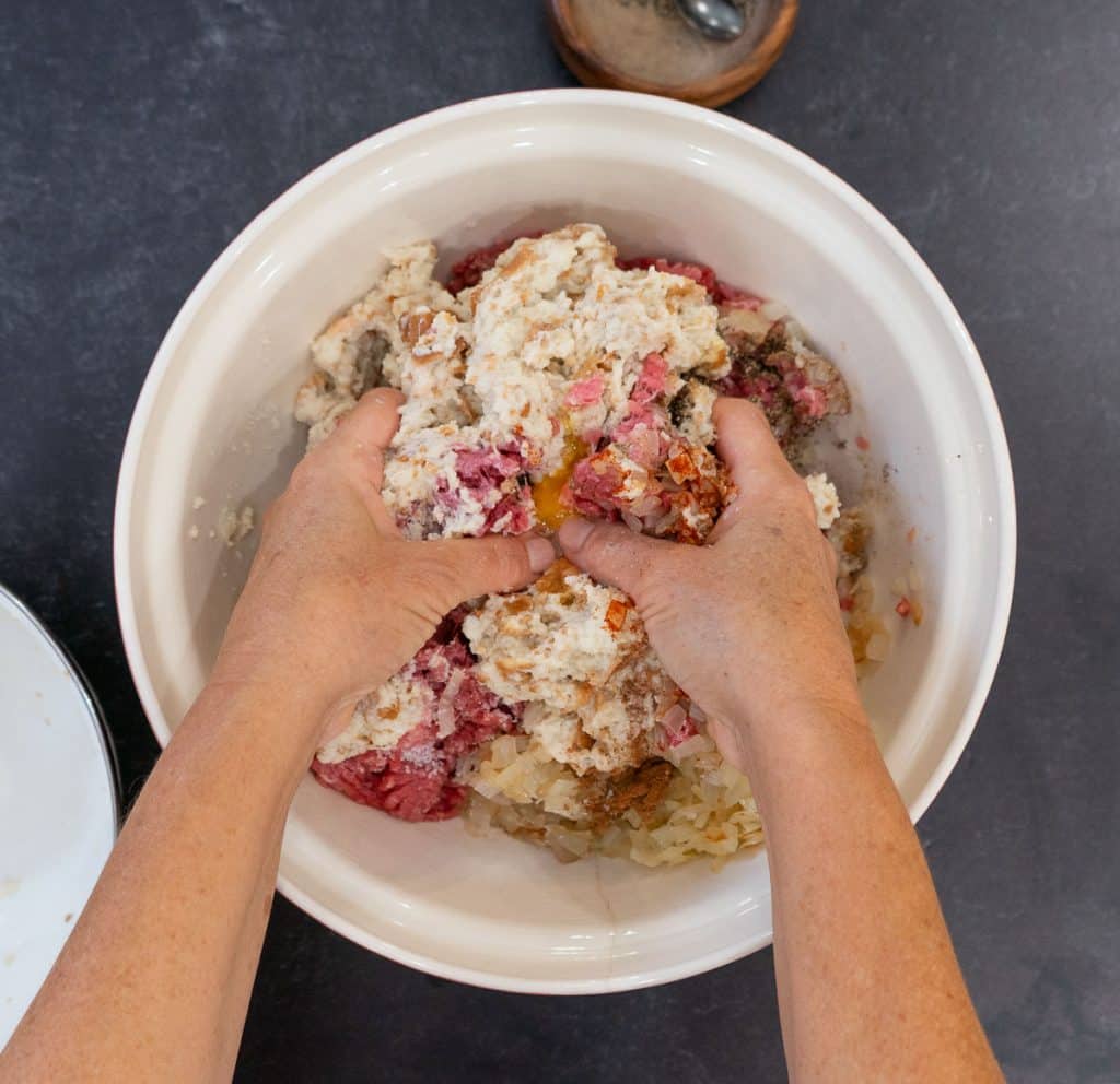 hands mixing swedish meatball ingredients together