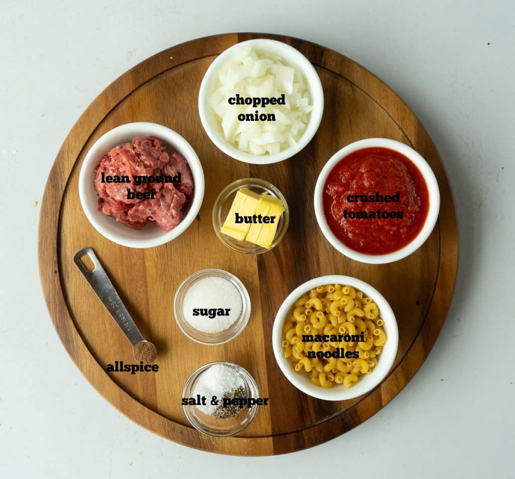 ingredients for goulash on a wood tray that is sitting on a white table