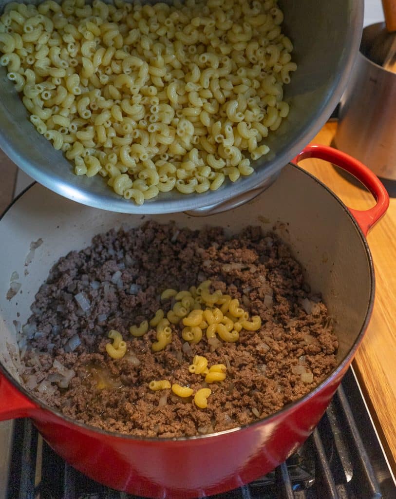 pouring cooked noodles in to meat mixture