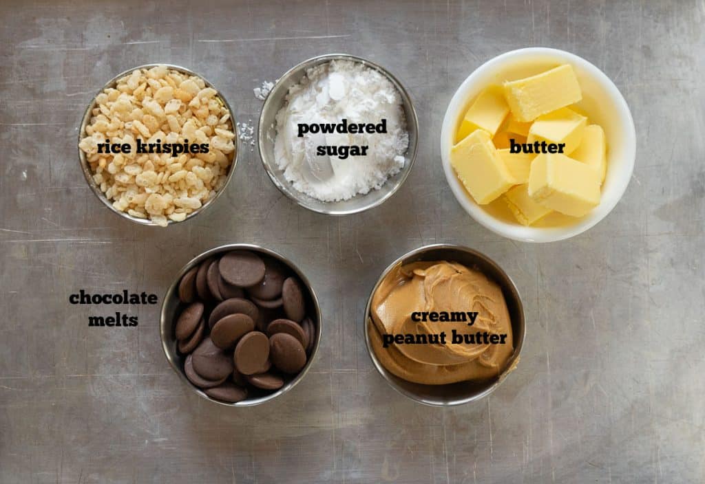 ingredients for peanut butter balls on a baking sheet: peanut butter, rice krispies, powdered sugar, butter, chocolate chips