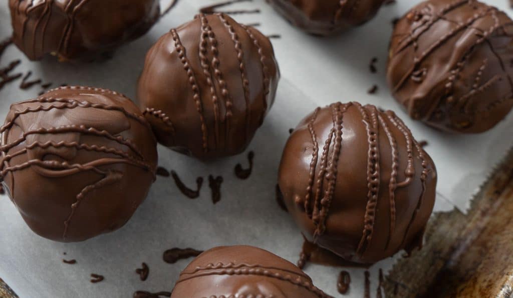 chocolate covered peanut butter balls on a parchment lined baking sheet