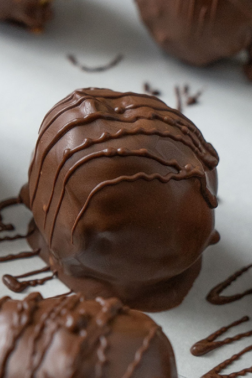 chocolate covered peanut butter ball on chocolate drizzled parchment paper