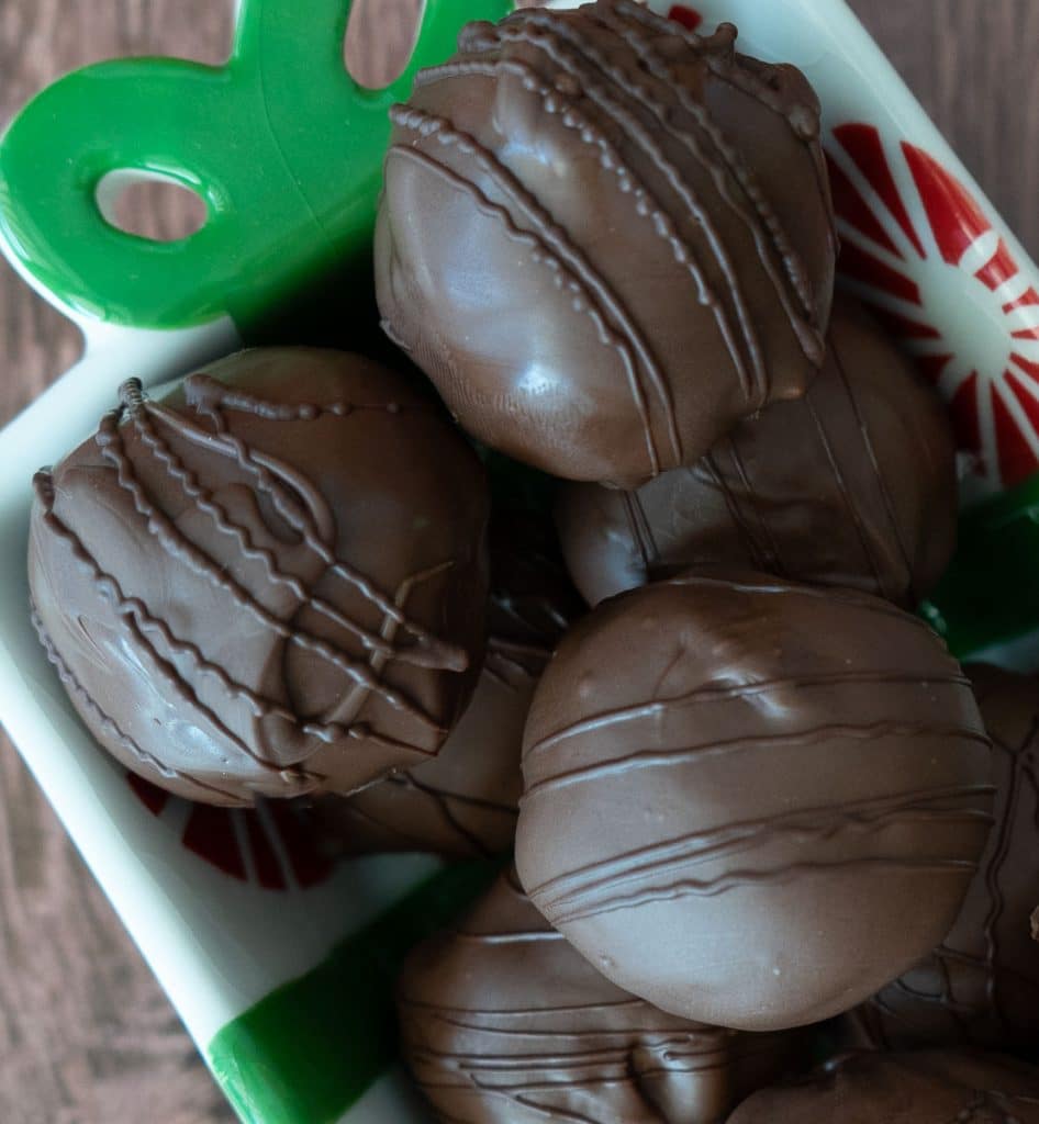 chocolate covered peanut butter balls sitting in a christmas dish