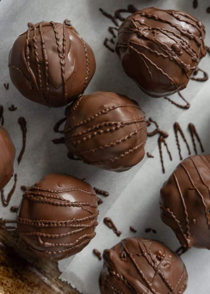 chocolate covered peanut butter balls on a baking sheet lined with parchement paper